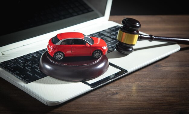 Toy car and legal gavel resting on a laptop keyboard.