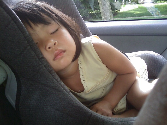 A little girl peacefully sleeping in a child car seat