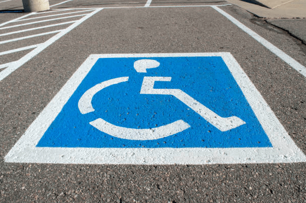 Handicap parking sign painted on ground with wheelchair symbol and blue background
